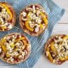 Pita pizza met paprika en feta, op een ovenrek met een blauwe doek eronder.
