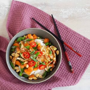 Vegetarische mihoensalade met ei, wortel, boontjes en veel rode peper. De mihoen is bestrooid met pinda's en naast de kom liggen eetstokjes.
