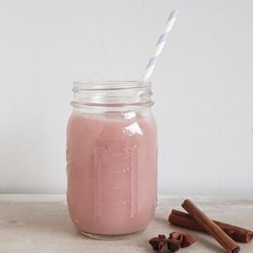 Smoothie met stoofpeertjes, kaneel en steranijs in een groot glas met een rietje.