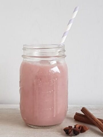 Smoothie met stoofpeertjes, kaneel en steranijs in een groot glas met een rietje.