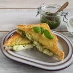 Tosti met mozzarella en pesto, de mozzarella-tosti is dik belegd en gebakken met parmezaan aan de buitenkant, waardoor de tosti een krokant kaaskorstje heeft.