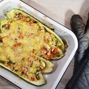 Gevulde courgettes met paprika en champignons in een ovenschaal. De gevulde courgettes zijn gegratineerd met kaas.