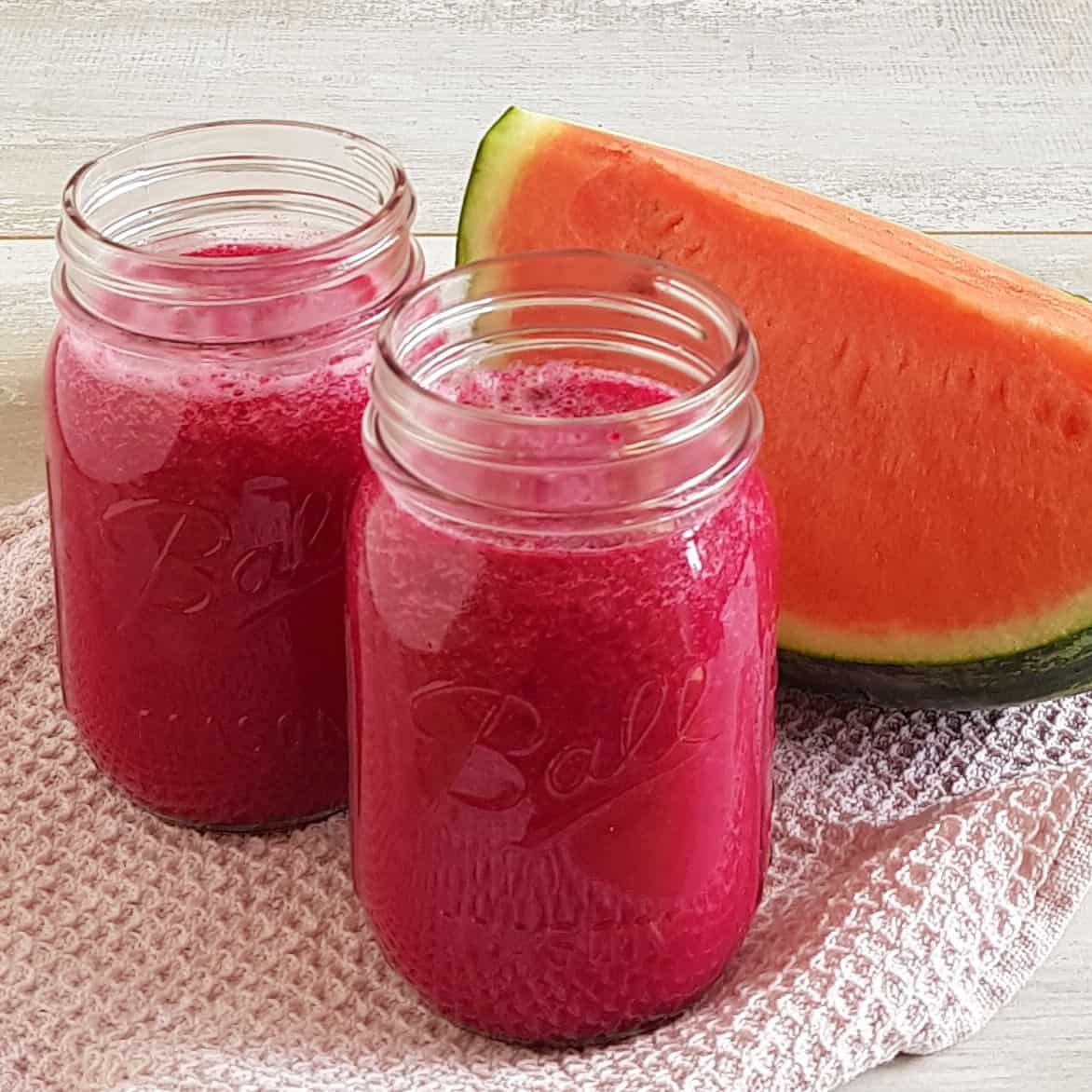 Smoothie met watermeloen rode biet in grote glazen Mason Jars. Op de achtergrond ligt een grote part watermeloen.