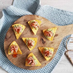 Tortillachips met garnalen op een houten serveerplank.