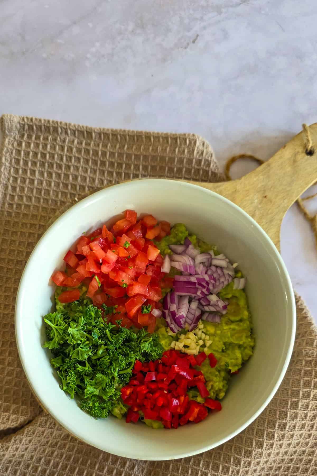 De toppings voor guacamole, uitgespreid over geprakte avocado.