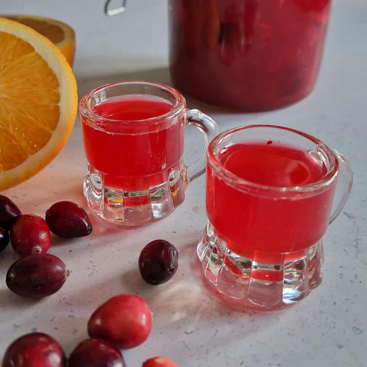 Cranberry likeur maken is simpel en leuk. In dit artikel vertel ik je hoe. Op de foto twee glaasjes met cranberrylikeur.