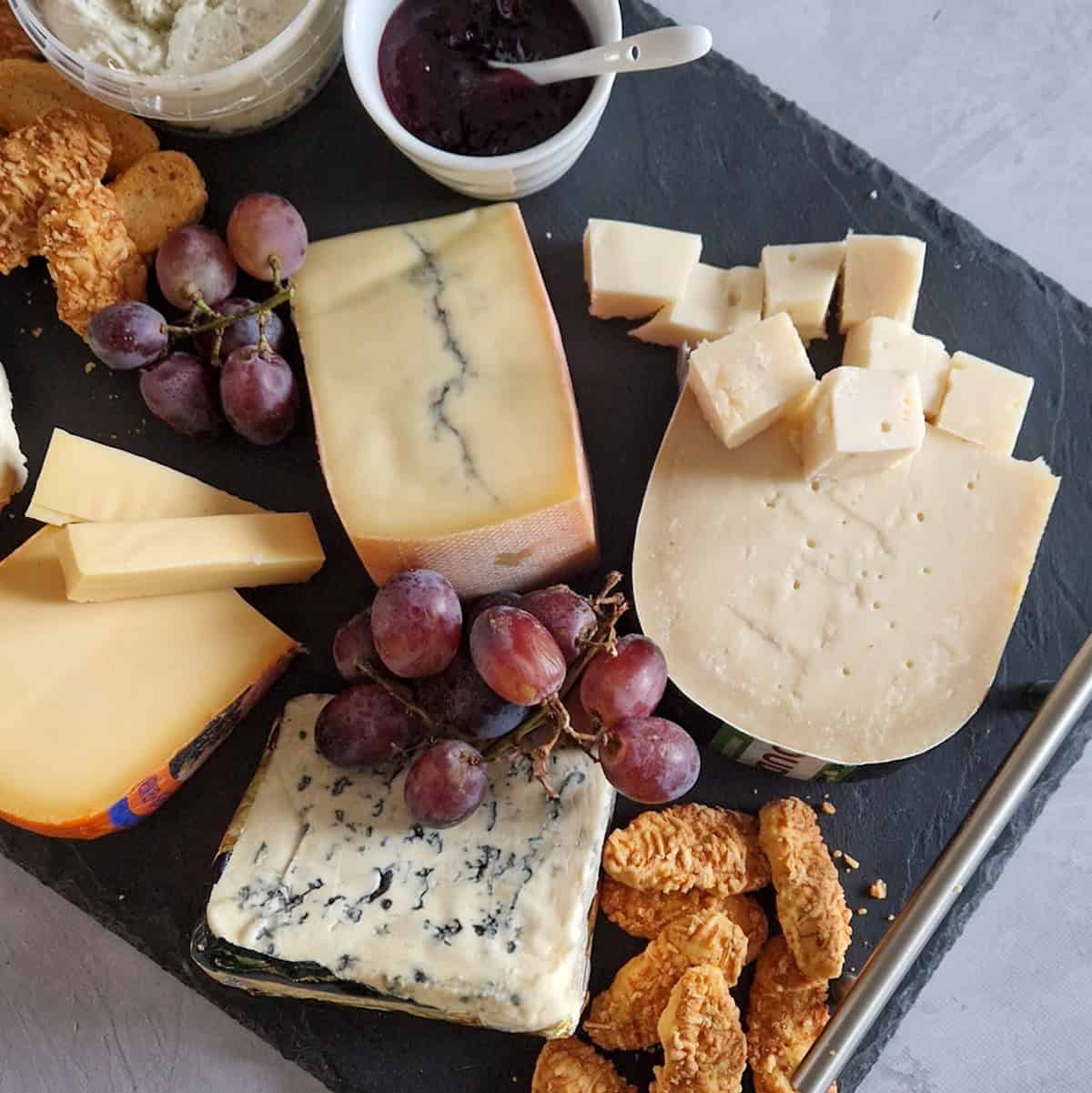 Een borrel kaasplank met verschillende soorten kaas en bijgerechtjes.