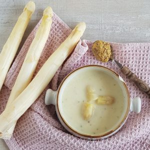 Aspergesoep in een ouderwetse soepkom. De soep is gegarneerd met aspergekopjes.