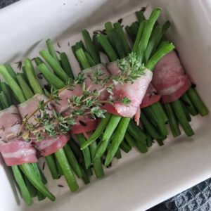 Close up van een ovenschaal gevuld met bosjes haricots verts met spek.