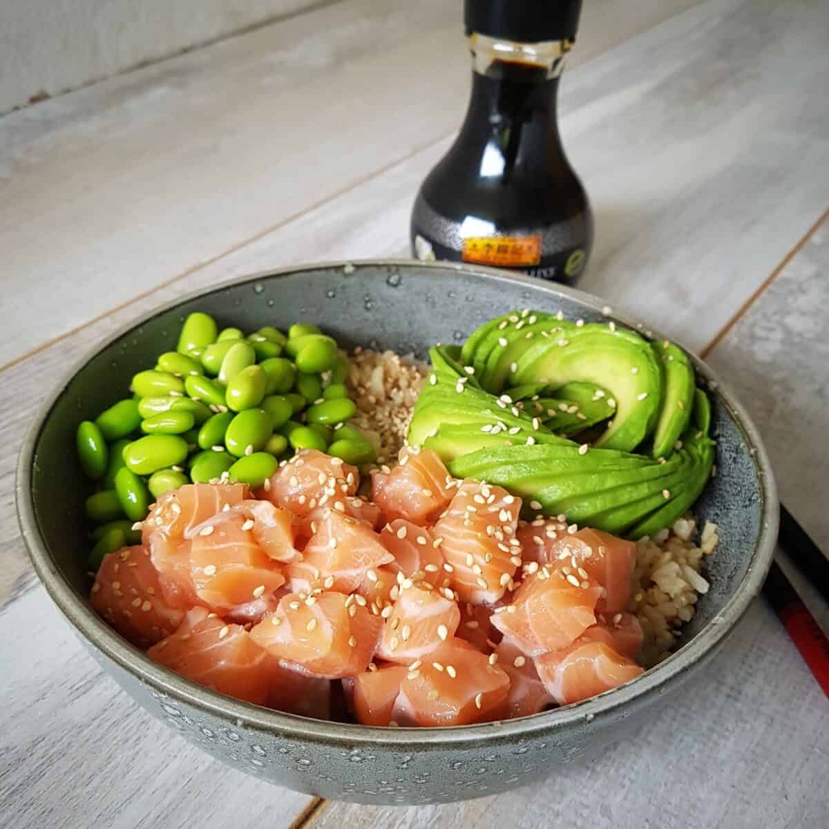 Een sushibowl met zalm een avocadoroos en edamame (sojabonen).