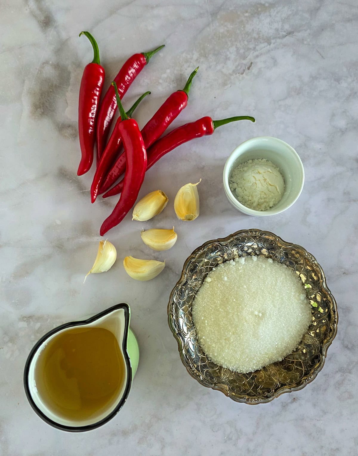 De ingrediënten voor het maken van sweet chilisaus op een wit marmeren ondergrond.