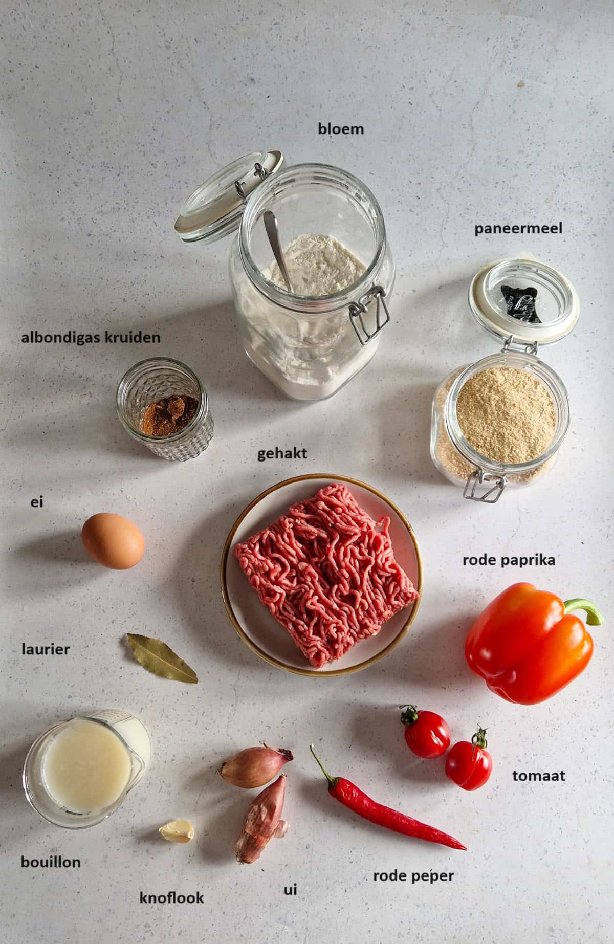 De ingrediënten voor Albondigas (Spaanse gehaktballetjes) op een witte ondergrond.