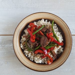 Beef Teriyaki op een bord, rijst met paprika, boontjes, ui en biefreepjes.