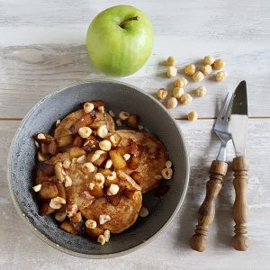 Spelt pannenkoeken met appel en hazelnoten in een kom.