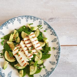 Gegrilde halloumi salade met courgette, sugar snaps en boontjes, op een bord.