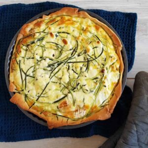 Courgettequiche, nog in de bakvorm. In de quiche zijn linten courgette en stukken geitenkaas verwerkt.
