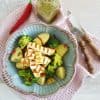 Gegrilde halloumi met aardappelsalade en broccoli, in een blauwe serveerschaal.
