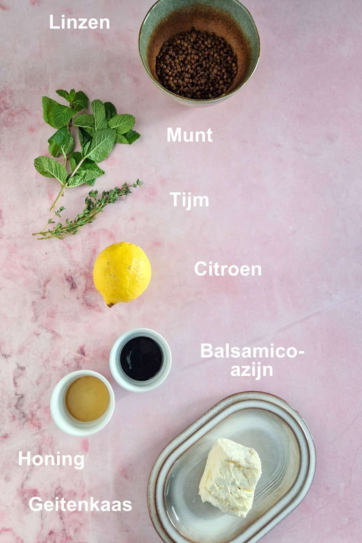 De ingrediënten voor een linzensalade met geitenkaas: linzen, geitenkaas, azijn, honing, citroen en verse kruiden.
