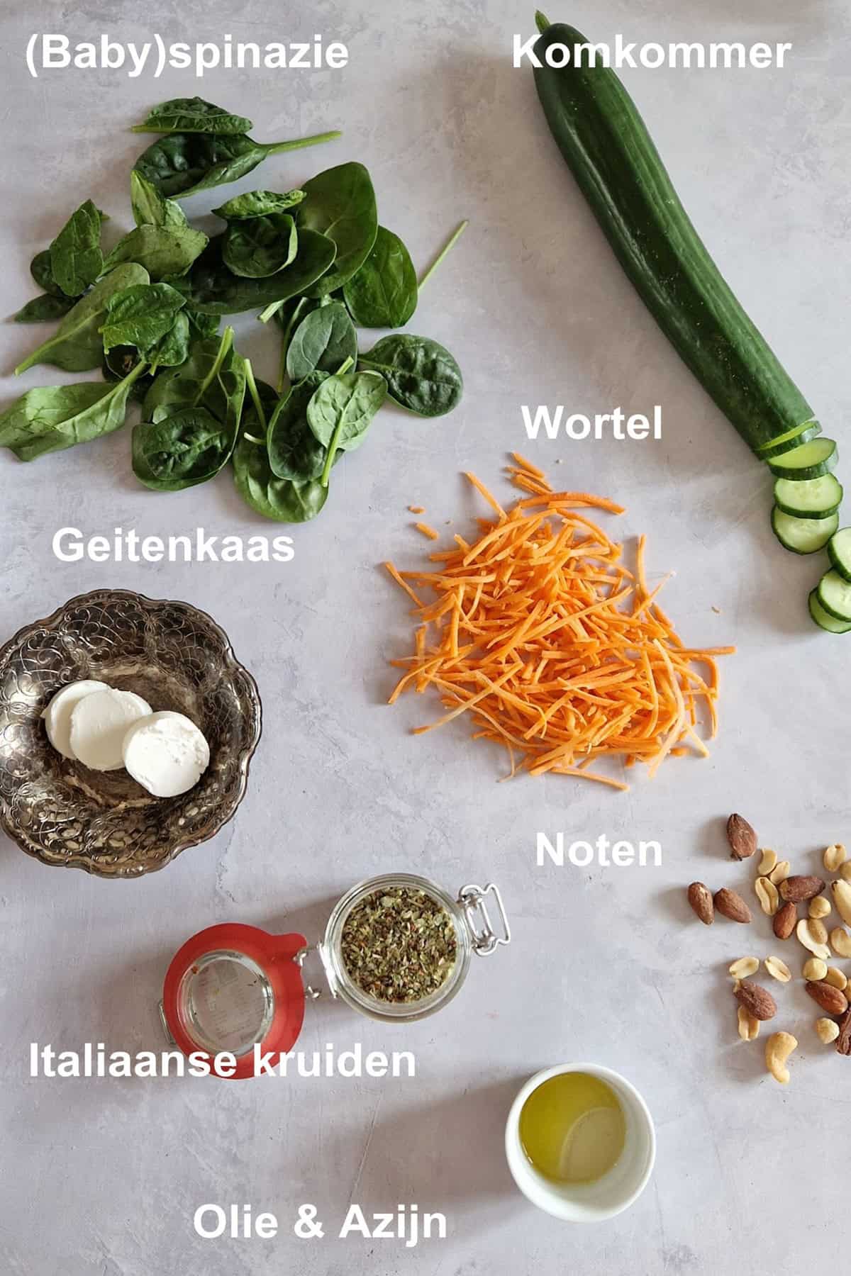 De ingrediënten om spinaziesalade met geitenkaas te maken, uitgestald op een lichte ondergrond.