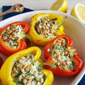Paprika uit de oven met spinazie, kaas en pijnboompitten. De rode en gele paprika's liggen in een ovenschaal, een kleurrijk geheel.