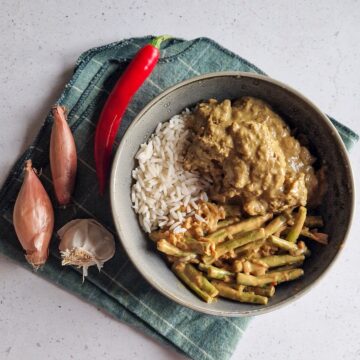 Een kommetje met rendang stoofvlees, rijst en boontjes.