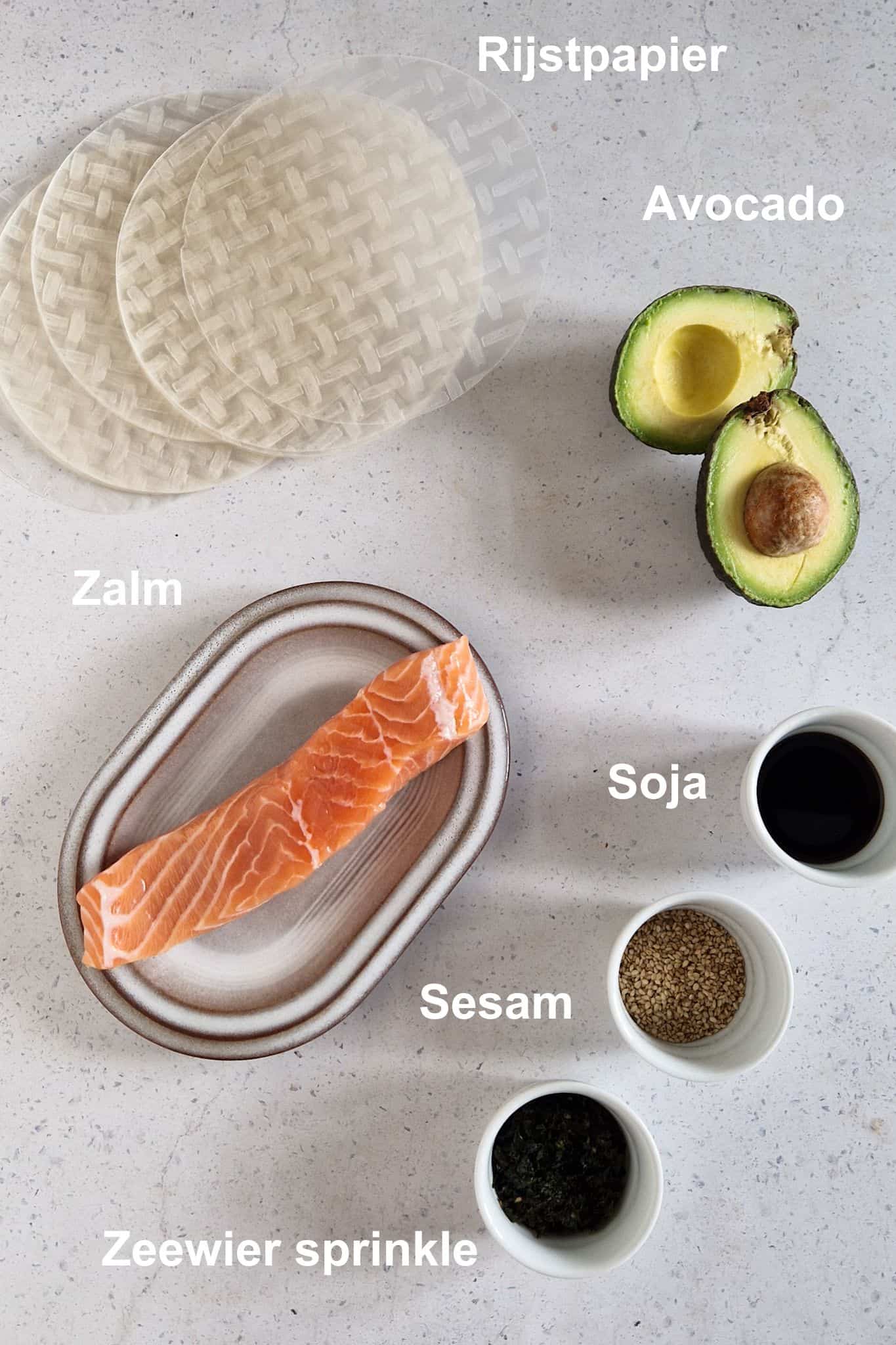 De ingrediënten om spring rolls met zalm en avocado te maken: rijstpapier, zalm, avocado, sojasaus, sesamzaadjes en zeewier sprinkle.