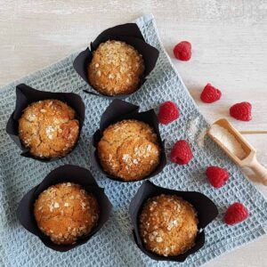 Frambozen ontbijtmuffins in papieren muffinvormpjes. De muffins zijn gegarneerd met havermout.