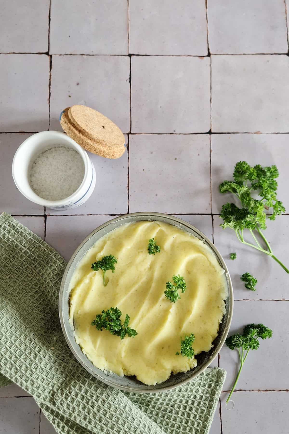 Het resultaat van een recept voor aardappelpuree: een kom gladde puree met zout en peterselie gegarneerd.