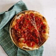 Een tarte tatin met tomaten. De taart ligt op een bord die op een groene doek ligt.