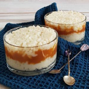 Rijstpudding met karamel in glazen kommetjes. De foto is van voren geschoten zodat je de laagjes rijstpudding en gezouten karamel goed kunt onderscheiden.