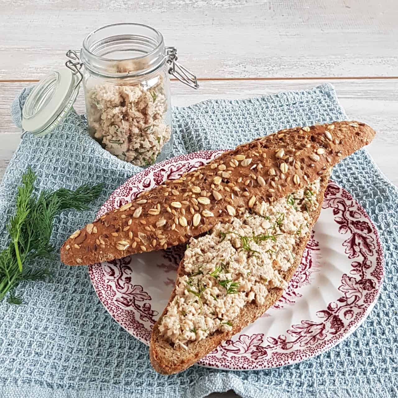 Zalmsalade op een volkoren broodje met pitten. De zalmsalade is bestrooid met verse dille.