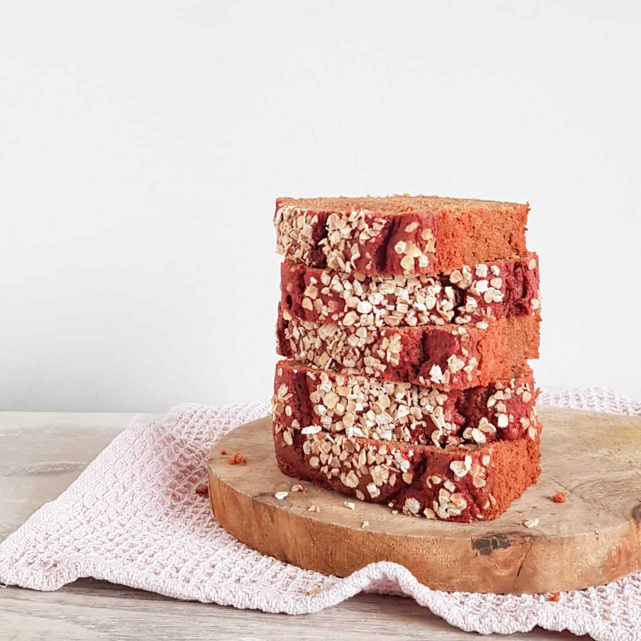 Bietencake of Bietenbrood: vijf plakken roze cake zijn op elkaar gestapeld op een houten serveerplank.