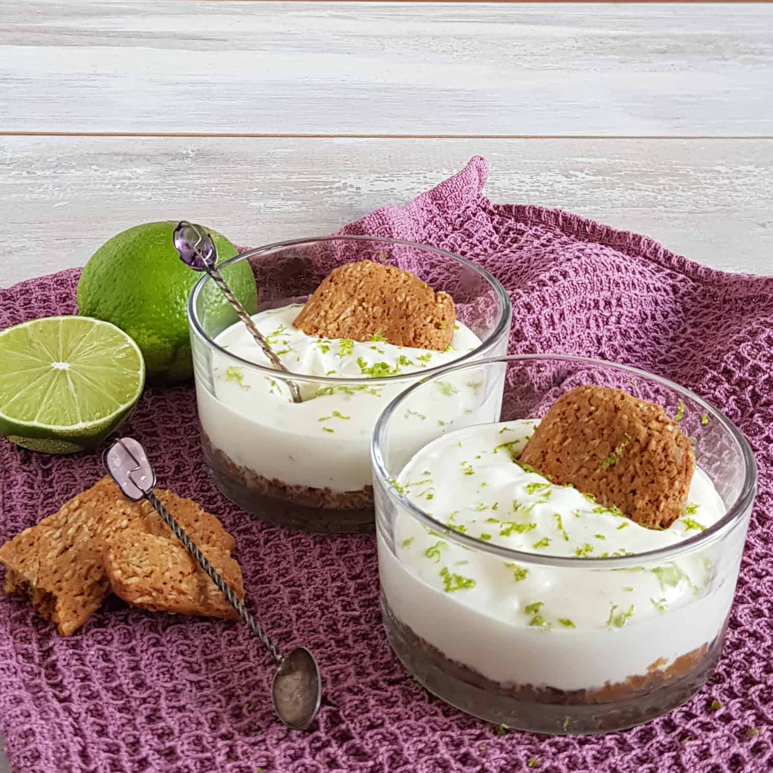 Toetje met gemberkoekjes en een witte mousse in glazen schaaltjes. De gembertoetjes zijn gegarneerd met een gemberkoekje en limoenrasp.