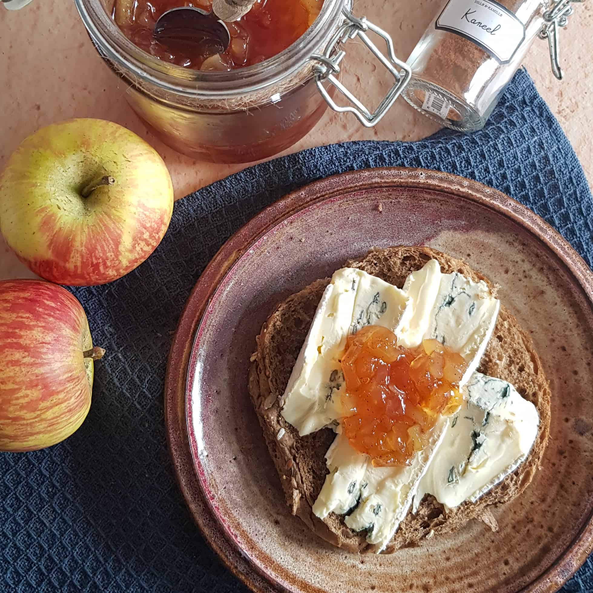 Appel-perenjam op een broodje gorgonzola. Het broodje ligt op een ouderwets bruin bordje.