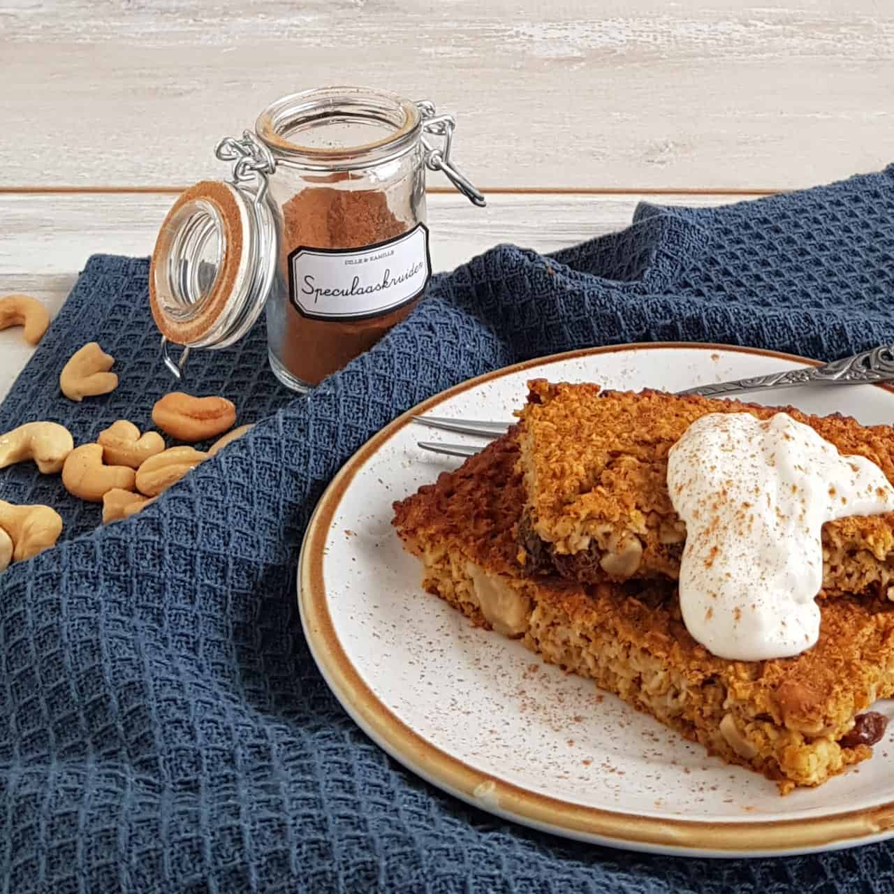Pompoen ontbijtbars op een klein bordje. De havermoutrepen met pompoen zijn gegarneerd met een schep yoghurt en kaneel.