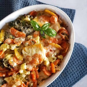 Italiaaanse groentenschotel: diverse groenten zoals broccoli en wortel, in een ovenschaal. De ovenschotel is gegratineerd met kaas en gegarneerd met verse basilicum.