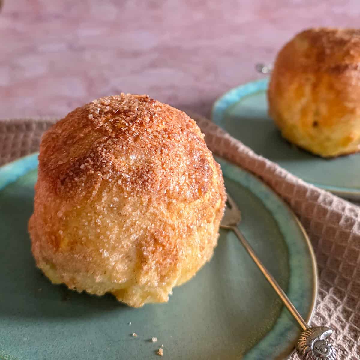 Appelbollen met spijs en rozijnen. Twee appelbollen op een gebaksbordje, met een vorkje ernaast.