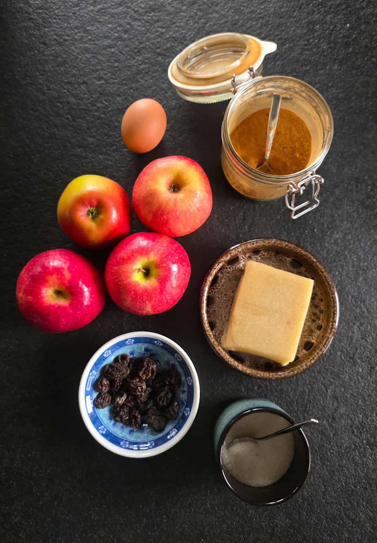 De ingrediënten voor dit appelbollen recept: appels, spijs, rozijnen, speculaaskruiden, suiker, een ei en vers bladerdeeg (niet op de foto).