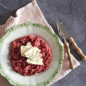 Bietenrisotto gegarneerd met drie flinke plakken blauwe kaas.