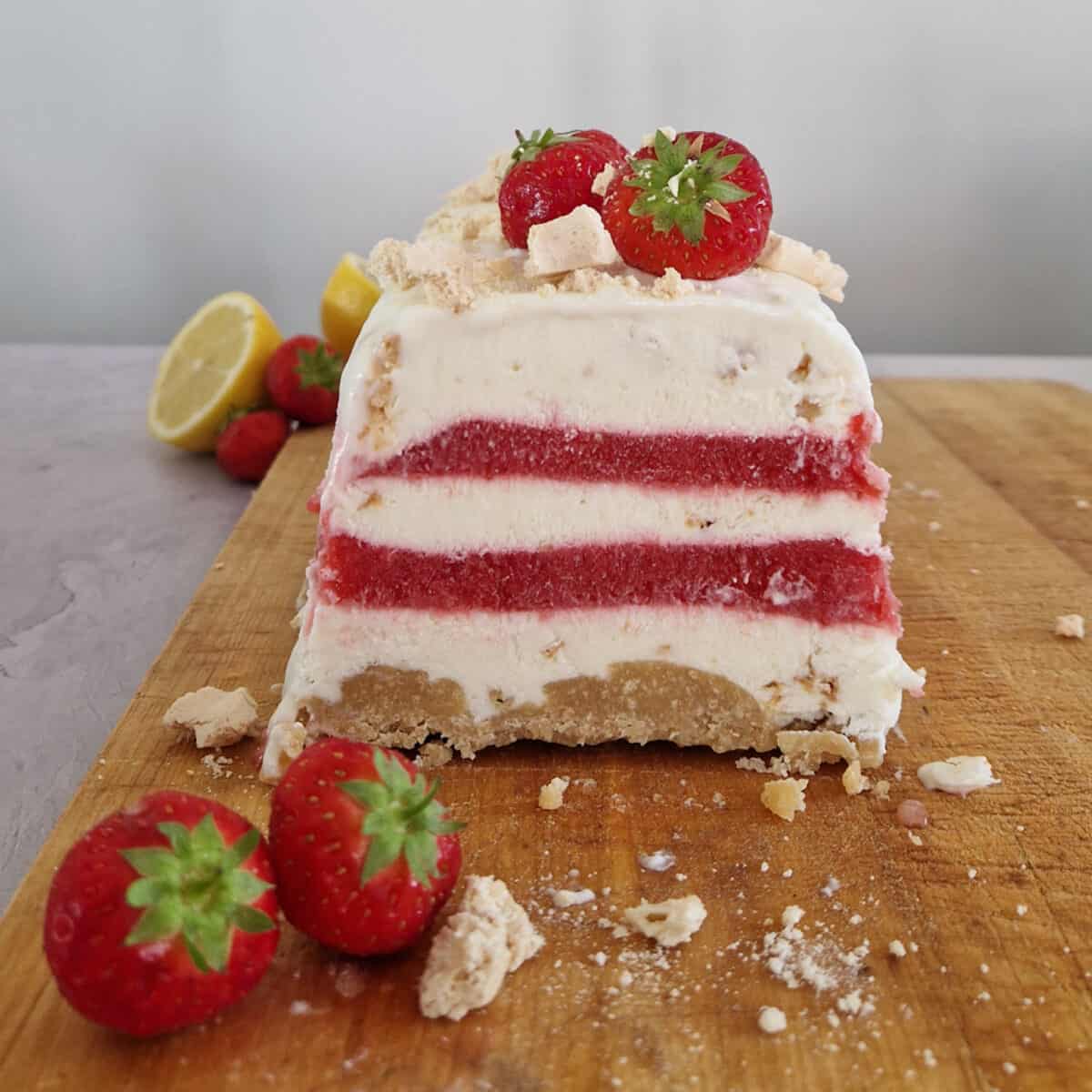 IJstaart met aardbeien, de foto is van voren genomen zodat de lagen aardbei, crème en de bodem van koek, goed van elkaar te onderscheiden zijn.