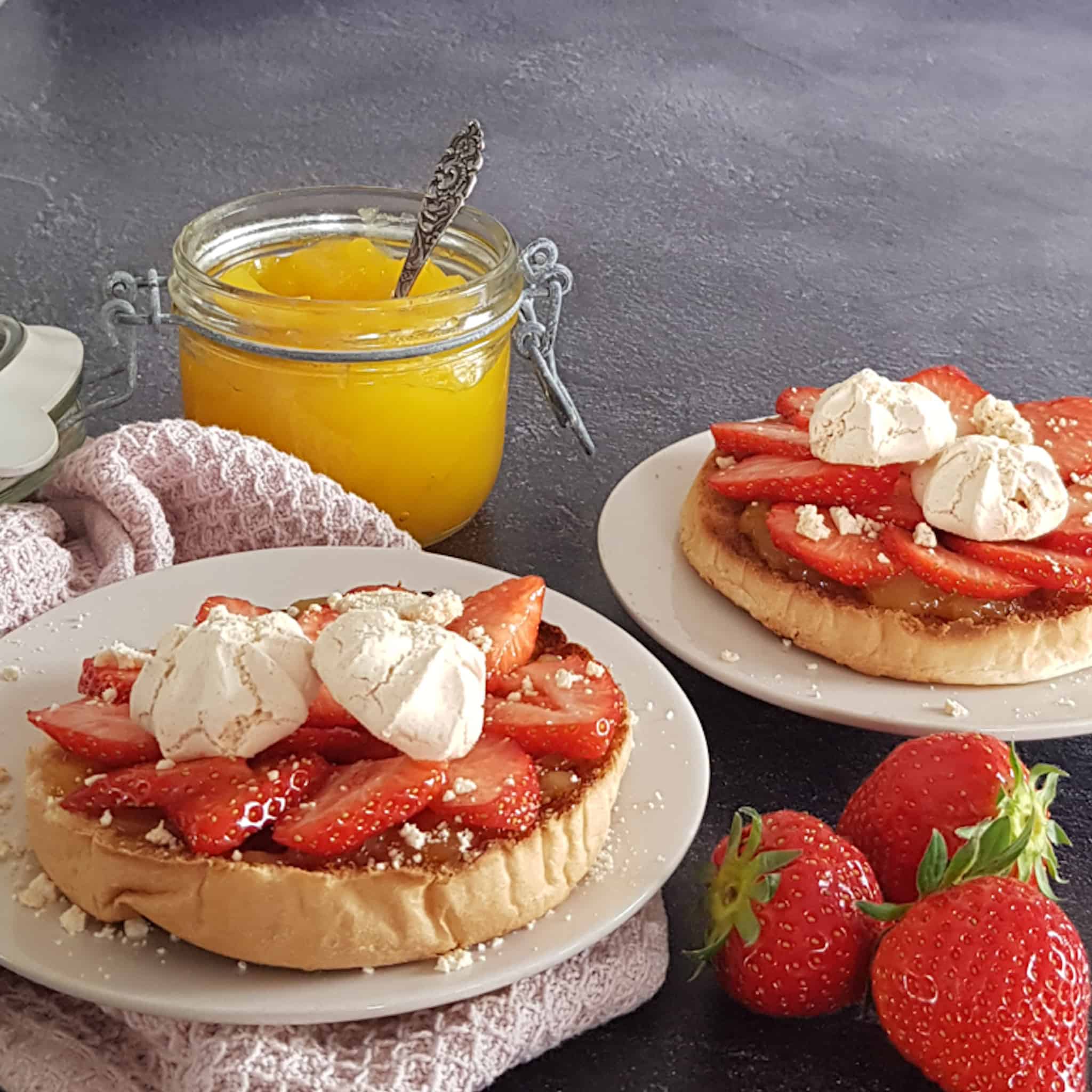 Beschuit met aardbei en lemon curd. De beschuitjes zijn gegarneerd met kleine meringues.