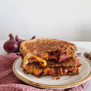 Tosti met cheddar en gekarameliseerde uien. De tosti is opengesneden waardoor de vloeibare cheddar zichtbaar is.