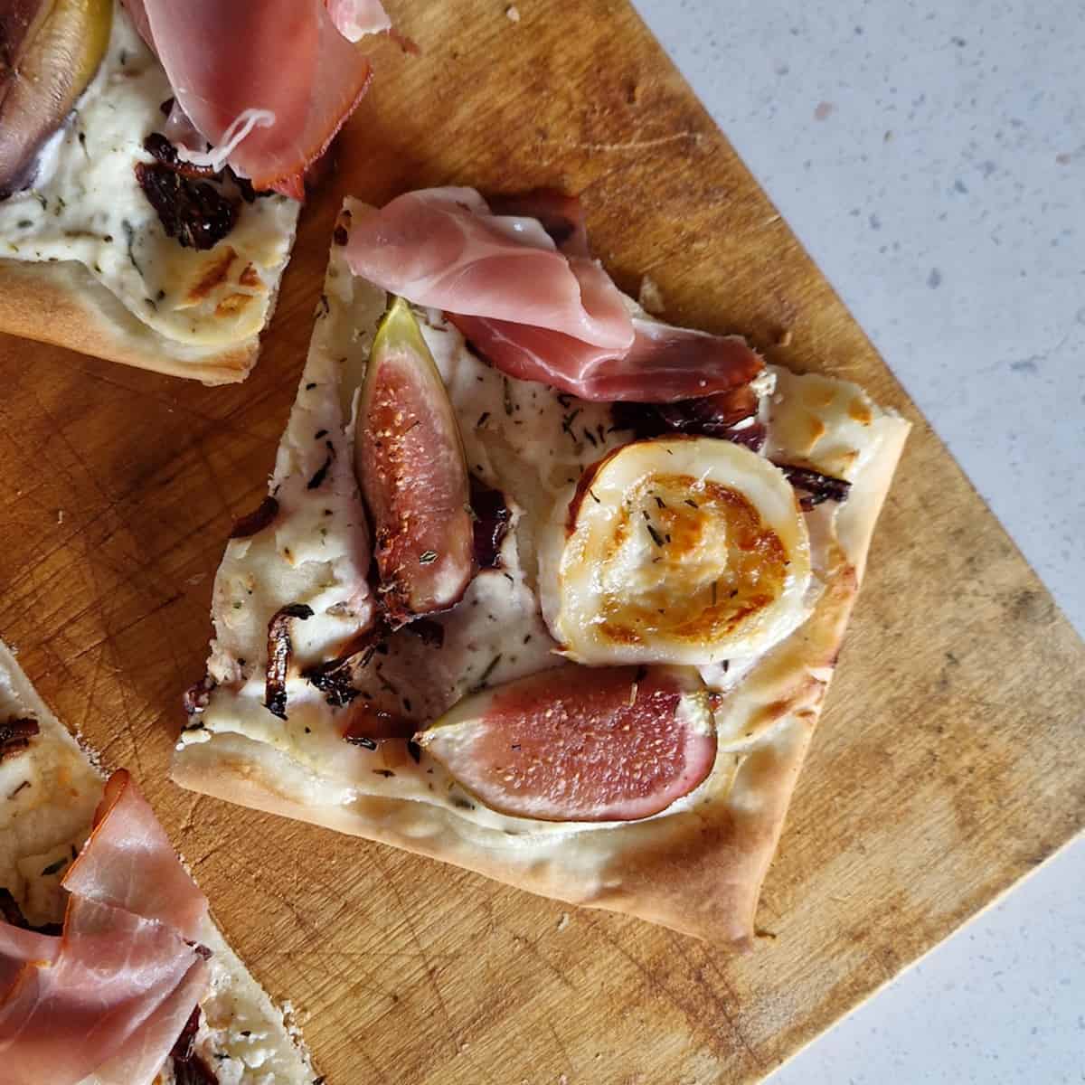 Een stukje flammkuchen met vijgen, geitenkaas en rauwe ham.