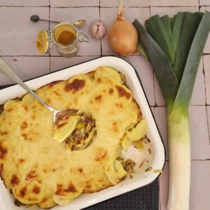 Preischotel met gehakt, ui en knoflook. De ovenschotel heeft een gratinlaagje en er is een lepel uit de schotel gehaald zodat de vulling zichtbaar wordt.