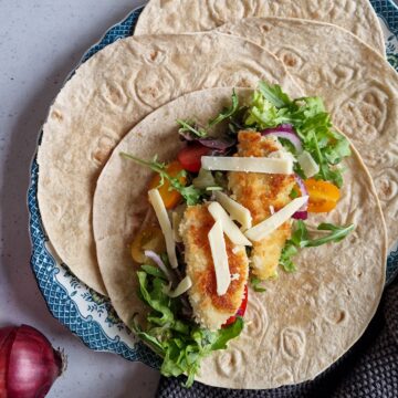 Wraps met krokante kip en sla. Het gerecht is bestrooid met flinters parmezaanse kaas.