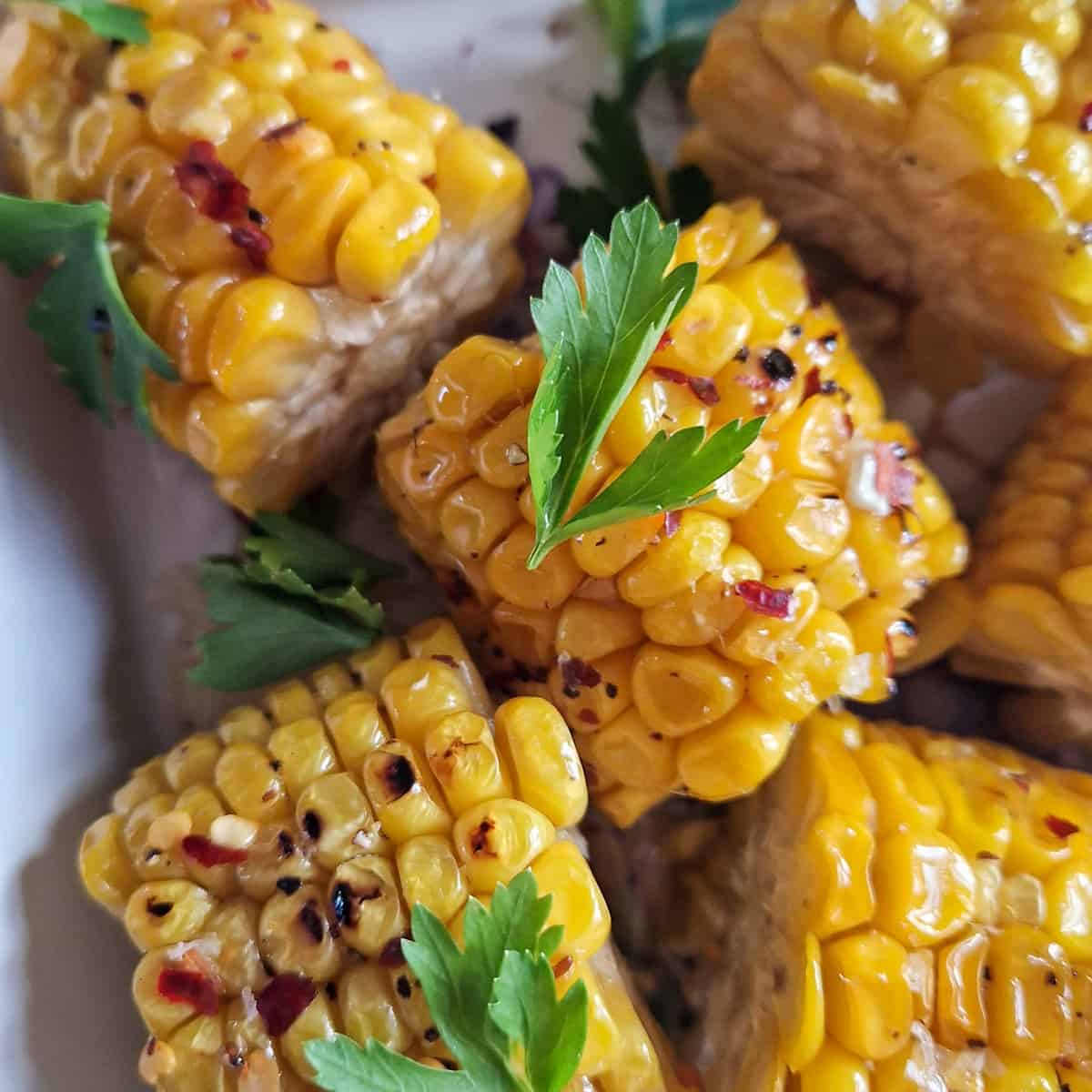 Een close-up van gesneden maiskolfjes met blaadjes peterselie erop.