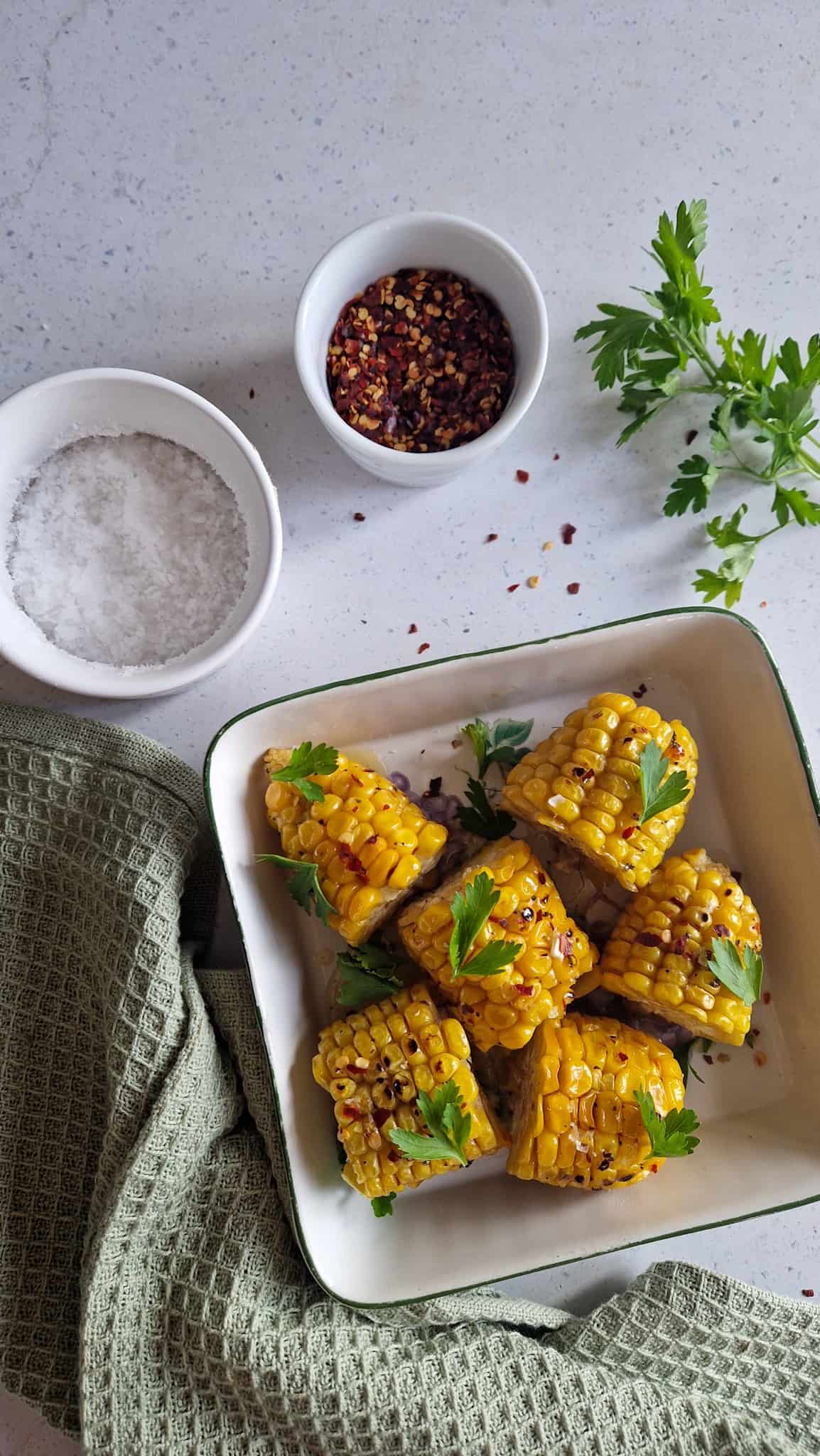 Een foto van het uiteindelijke gerecht: zes maiskolfjes met boter en honing en chilivlokken, in een serveerschaal.