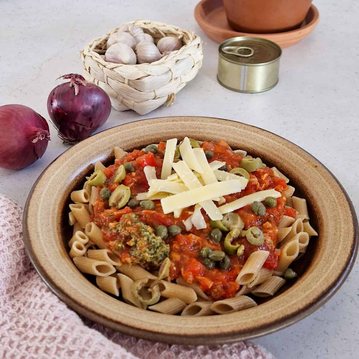 Een bord tonijnpasta met decoratieve ingrediënten er omheen