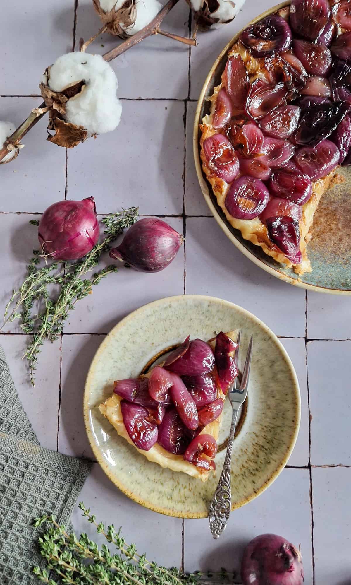 Een punt rode uien tarte tatin op een klein bordje, met de rest van de taart er schuin boven.