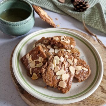 Een schaaltje speculaasbrokken met erachter een kopje thee.